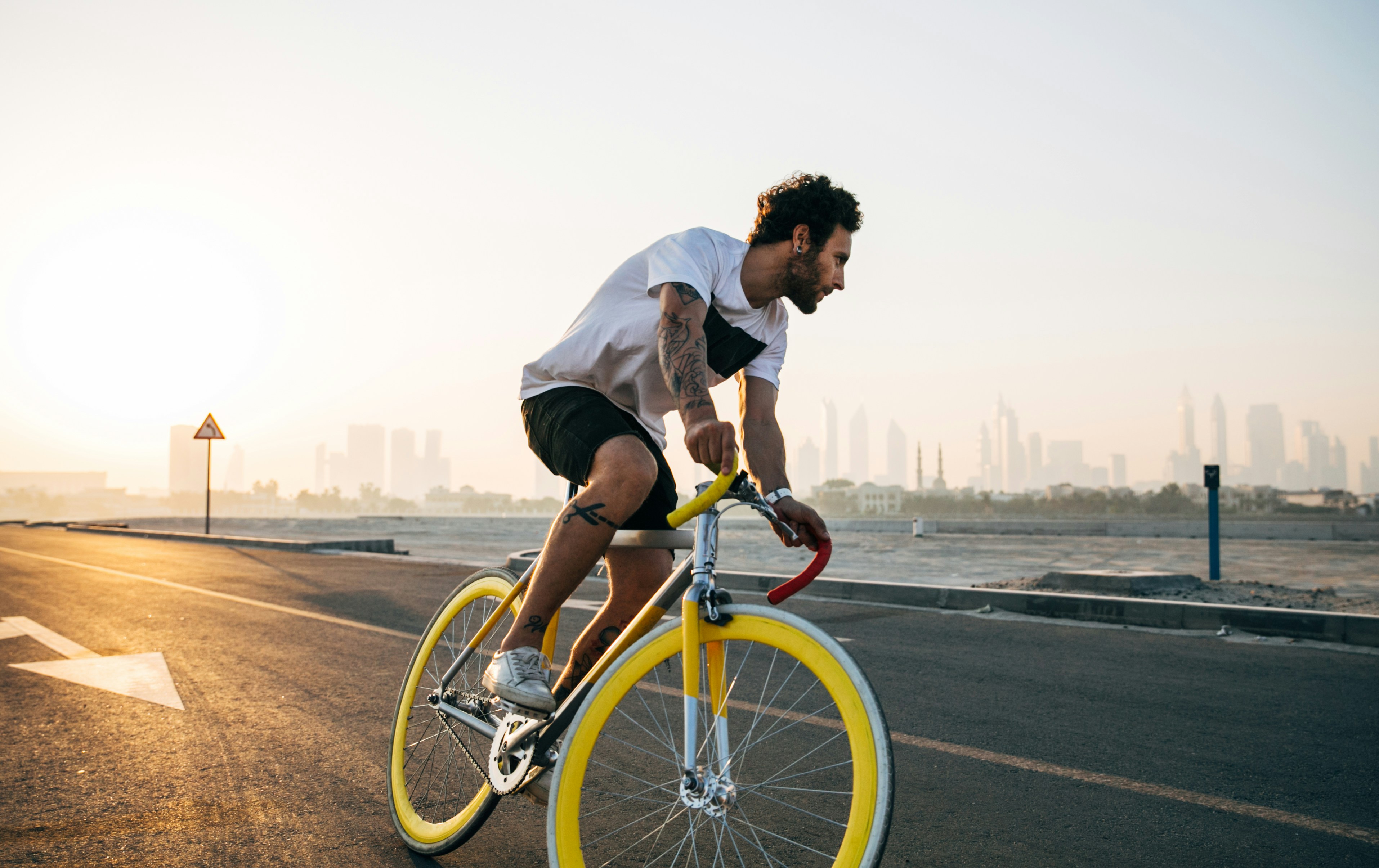 Cyclist riding at sunrise beside a city skyline